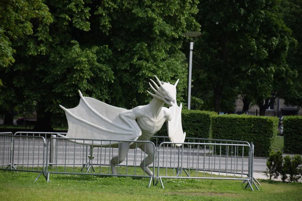 White dragon-like sculpture poised behind metal crowd barriers